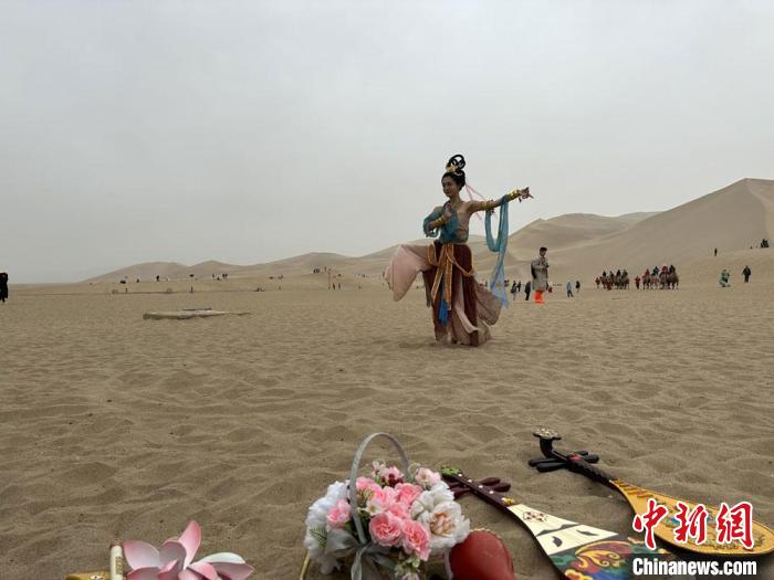 圖為2023年4月底，敦煌大漠“逐舞者”奧楠在鳴沙山月牙泉景區(qū)視頻直播敦煌舞?！●T志軍 攝