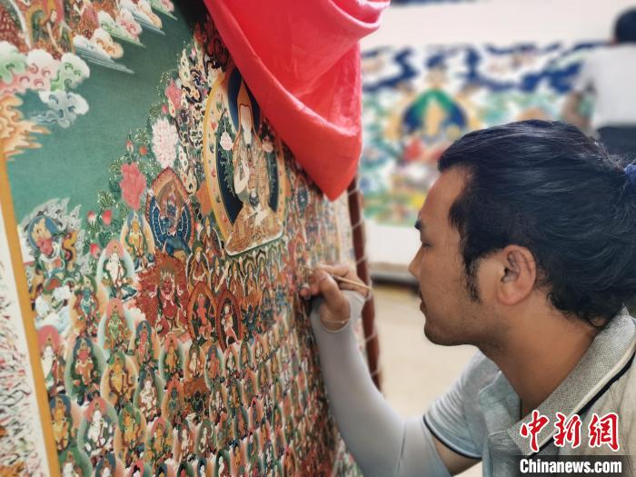 圖為更登才讓的徒弟繪畫唐卡?！?zhí)砀?攝